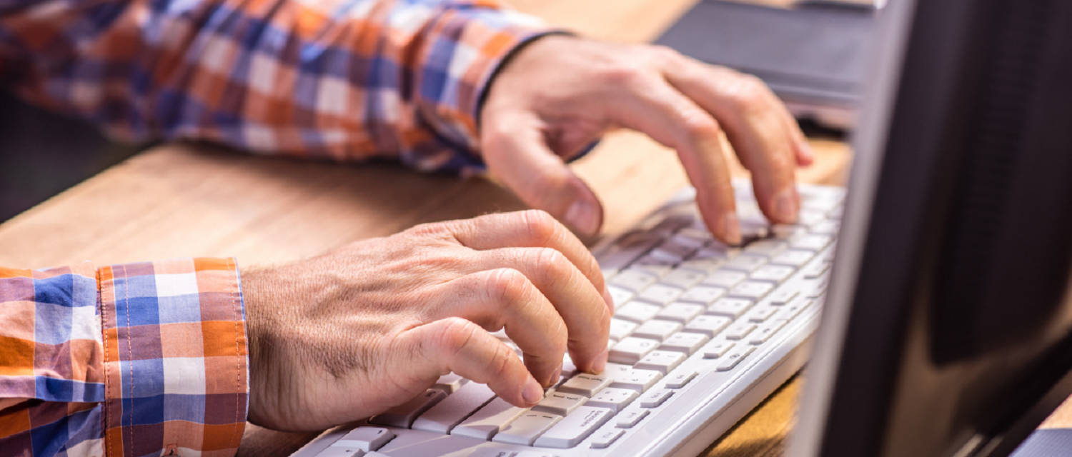Image of hands typing on a computer keyboard to write up summary of himself for a new job application