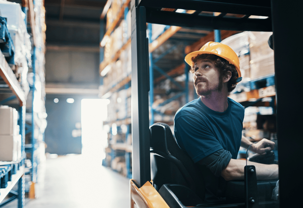 A contractor driving a forklift in a warehouse as part of his job in logistics and supply chain management.