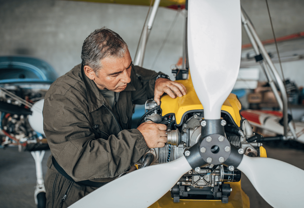 An aviation mechanic repairing the propeller of an aviation vehicle, representing contract work for mechanics with M&E Global.