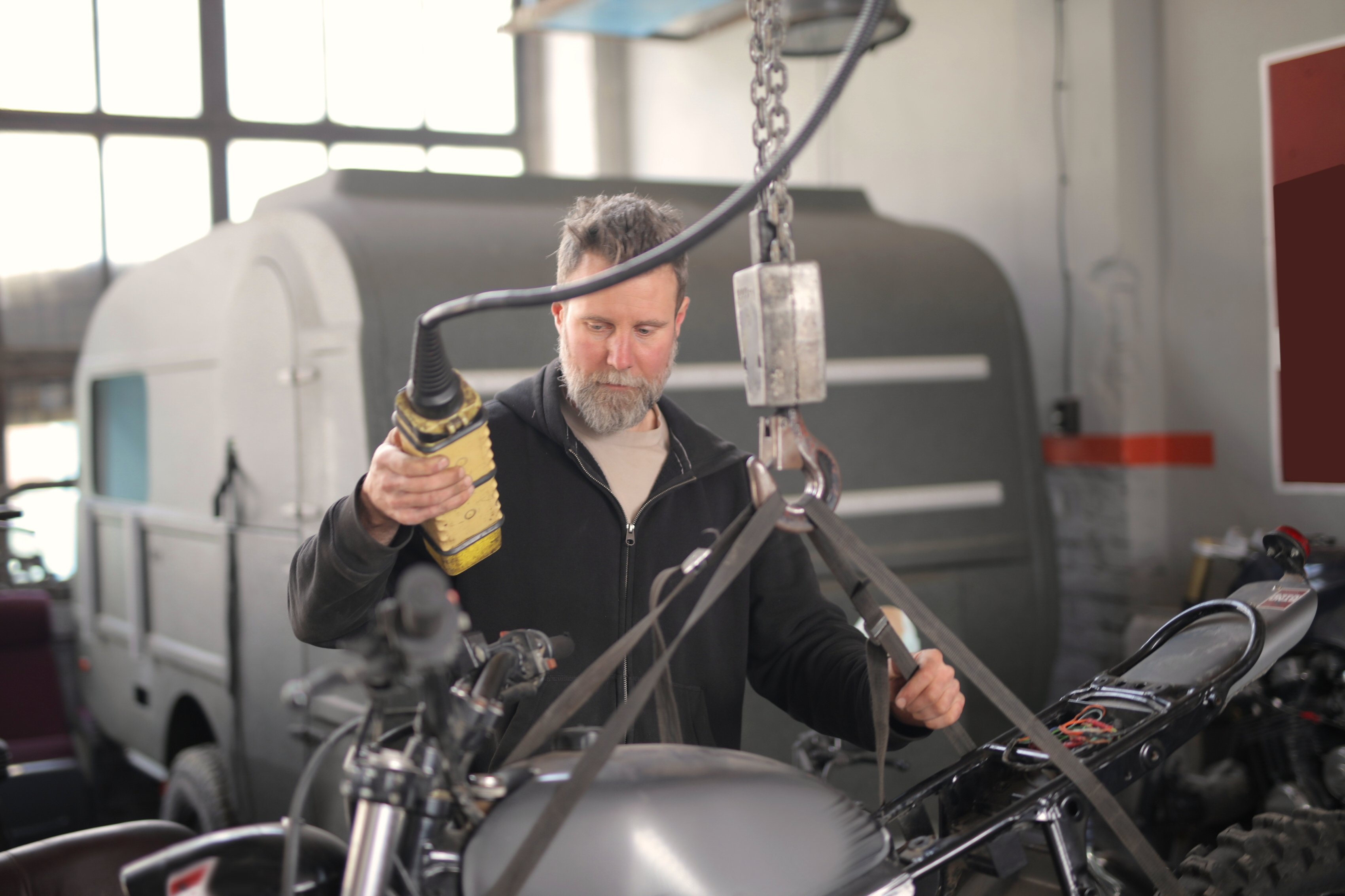 Canva - Male mechanic using hydraulic crane in garage