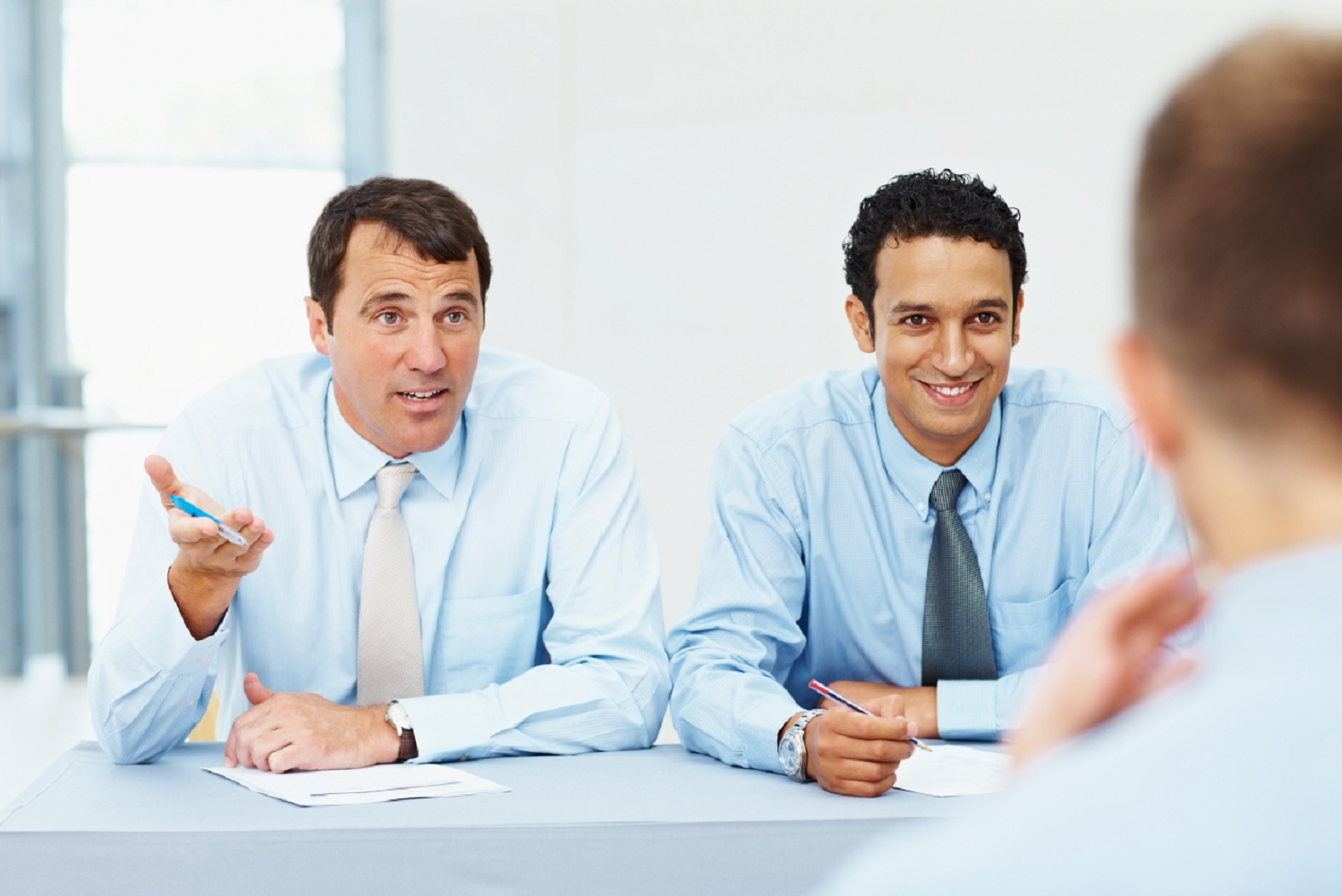 Two men conducting panel interview, with a male candidate