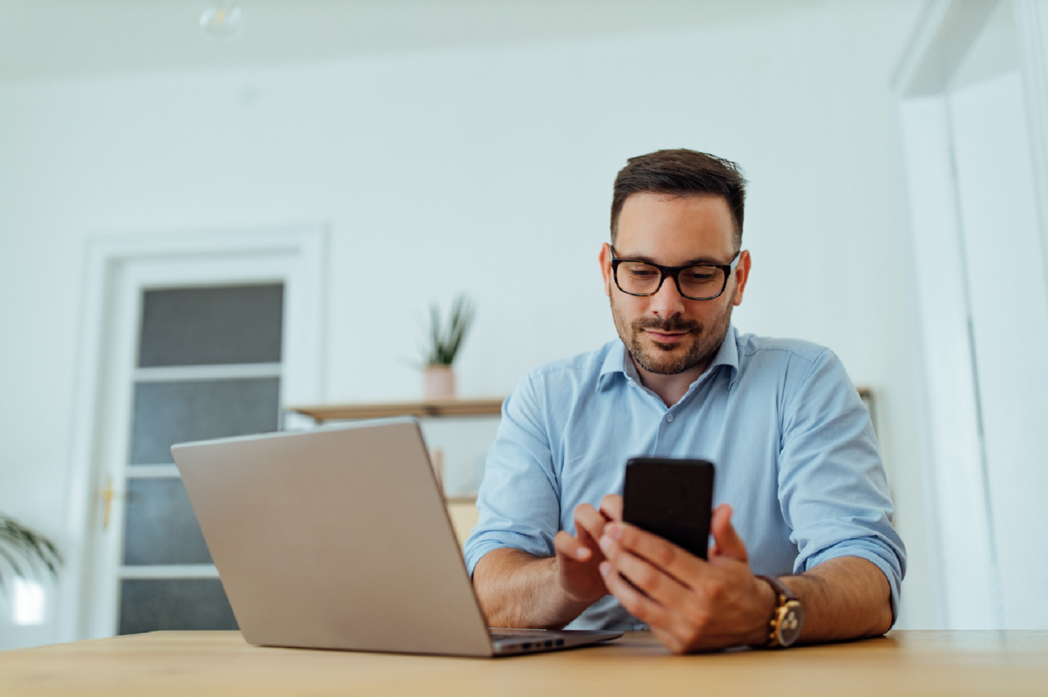 Man using his phone and laptop whilst using social to look for a new career